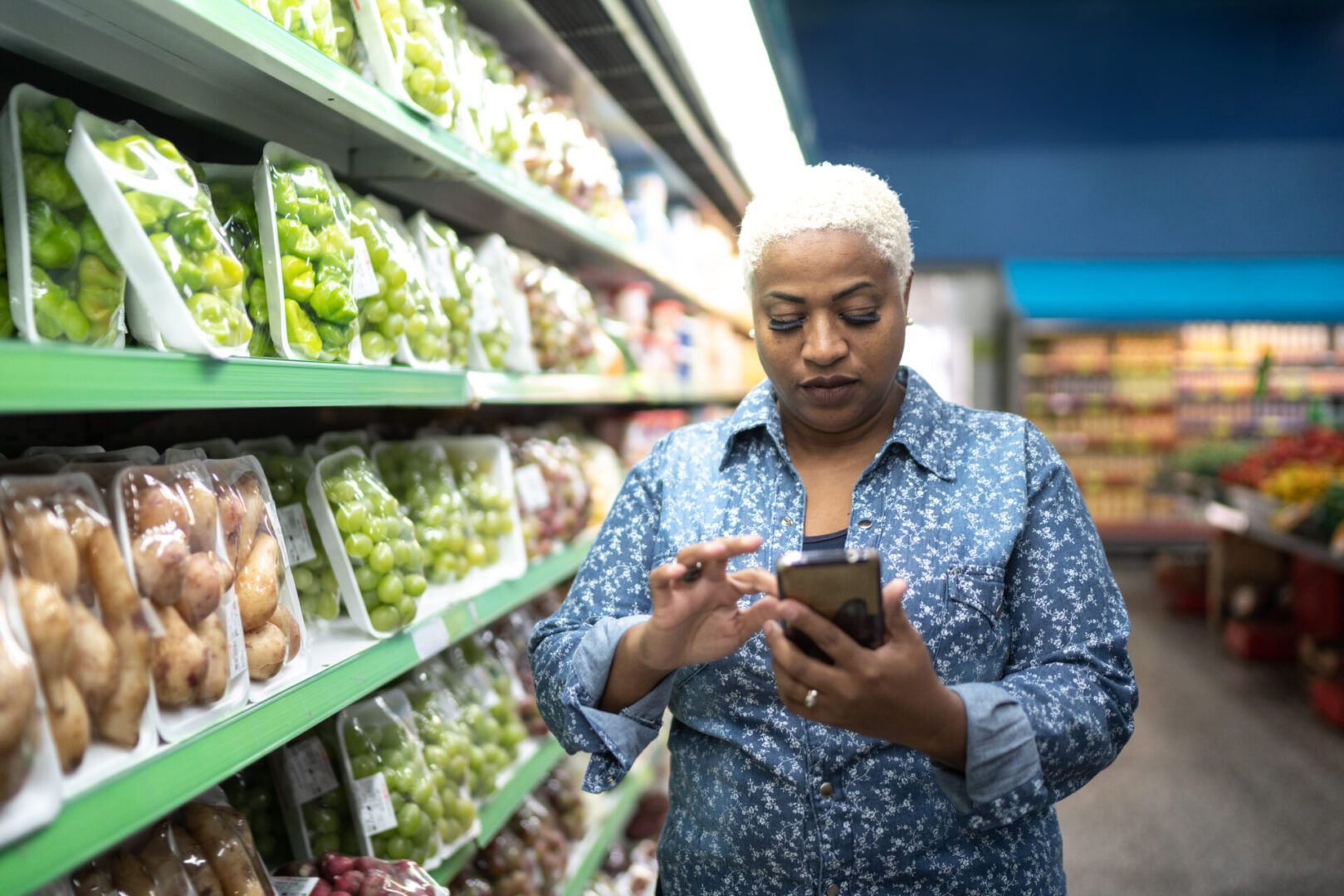 Woman buying at supermarket using mobile phone